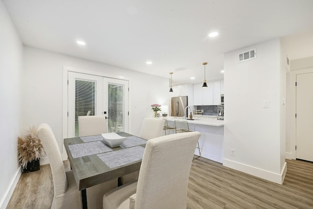 dining space with sink, light wood-type flooring, and french doors