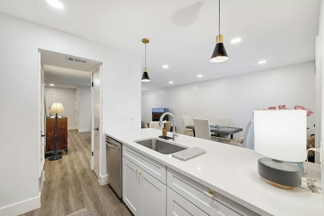 kitchen with sink, decorative light fixtures, light hardwood / wood-style floors, stainless steel dishwasher, and white cabinetry