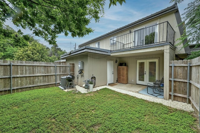 back of property featuring a patio, central AC unit, a balcony, french doors, and a lawn