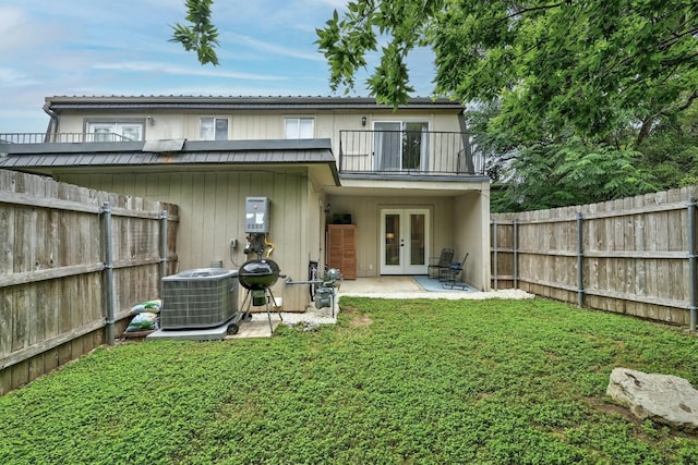 rear view of house with a balcony, a patio, french doors, cooling unit, and a yard