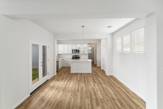 kitchen with white cabinetry, appliances with stainless steel finishes, backsplash, decorative light fixtures, and french doors