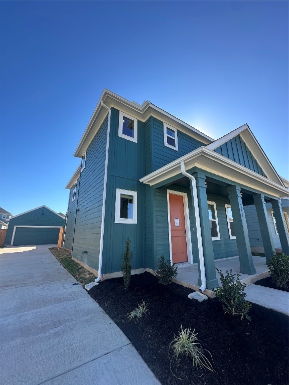 view of front of home featuring a porch, a garage, and an outbuilding