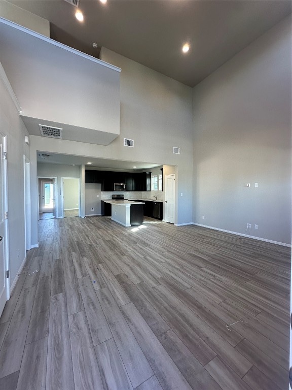 unfurnished living room featuring hardwood / wood-style floors and a high ceiling