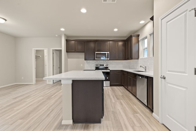 kitchen featuring a kitchen island, appliances with stainless steel finishes, sink, and backsplash