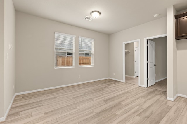 unfurnished bedroom featuring a walk in closet and light hardwood / wood-style flooring