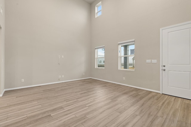 interior space with plenty of natural light, a high ceiling, and light wood-type flooring