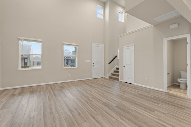 unfurnished living room with light hardwood / wood-style floors and a high ceiling