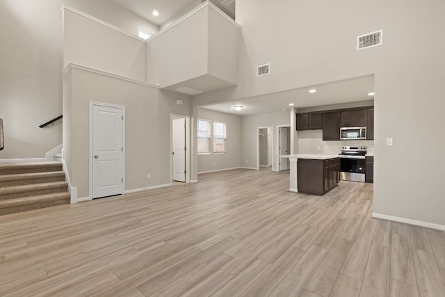 unfurnished living room with a towering ceiling and light hardwood / wood-style flooring