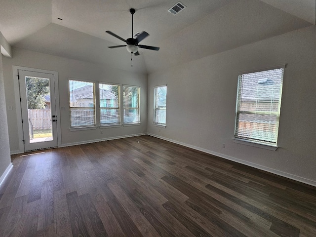 empty room featuring ceiling fan, a healthy amount of sunlight, dark wood-type flooring, and vaulted ceiling