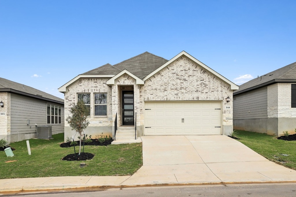 view of front of property with a garage, a front lawn, and central AC