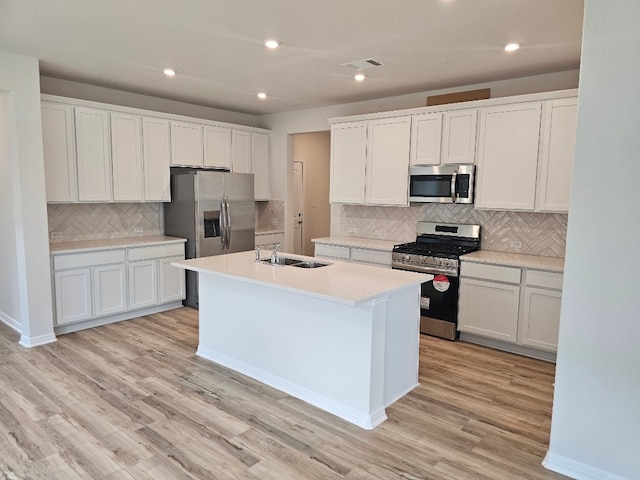 kitchen featuring appliances with stainless steel finishes, light hardwood / wood-style floors, a kitchen island with sink, and white cabinets