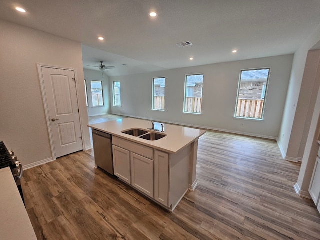 kitchen with sink, a center island with sink, white cabinetry, appliances with stainless steel finishes, and hardwood / wood-style floors