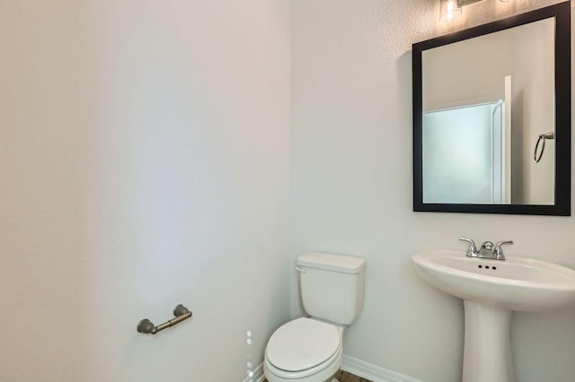 bathroom featuring a sink, baseboards, and toilet