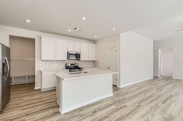 kitchen featuring visible vents, stainless steel appliances, light countertops, light wood-type flooring, and backsplash