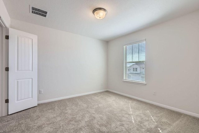 carpeted spare room featuring baseboards and visible vents