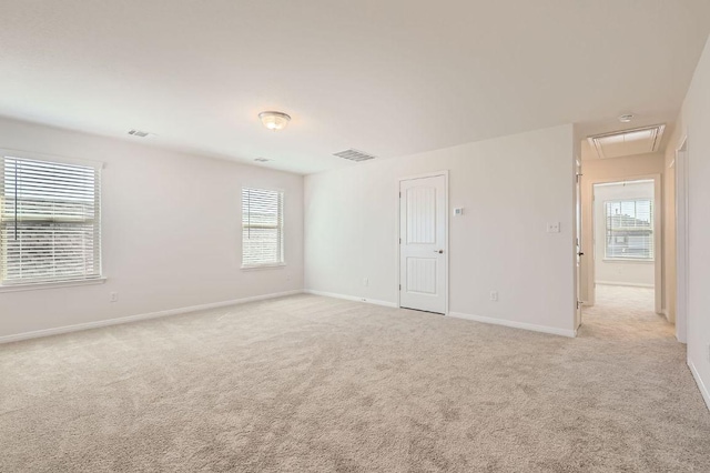 empty room with attic access, visible vents, baseboards, and light carpet