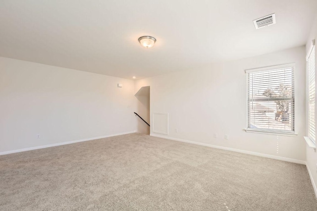 spare room featuring carpet, visible vents, and baseboards