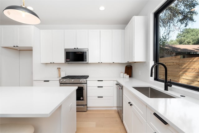 kitchen with white cabinets, pendant lighting, sink, and stainless steel appliances