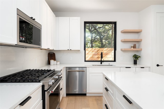 kitchen featuring appliances with stainless steel finishes, light hardwood / wood-style floors, white cabinetry, and sink