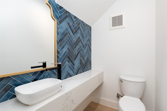 bathroom with lofted ceiling, tile walls, and toilet