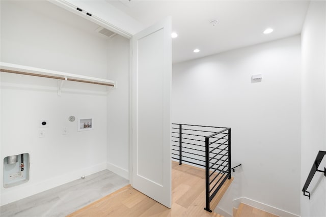 clothes washing area with electric dryer hookup, hookup for a gas dryer, washer hookup, and light hardwood / wood-style flooring