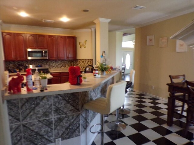 kitchen with kitchen peninsula, stove, backsplash, a breakfast bar, and crown molding