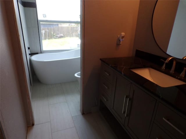 bathroom featuring vanity, a tub to relax in, and toilet