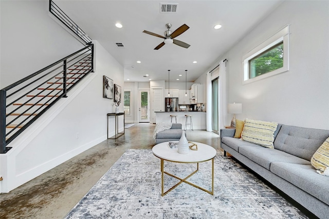 living room with ceiling fan, a wealth of natural light, and concrete floors