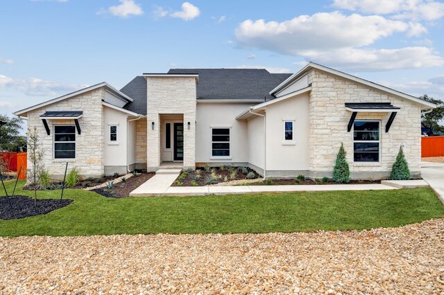 contemporary house featuring a front yard, fence, stone siding, and stucco siding