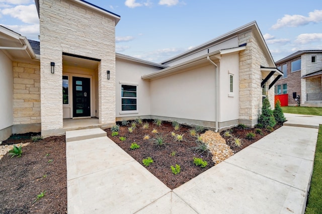 doorway to property with stucco siding and stone siding