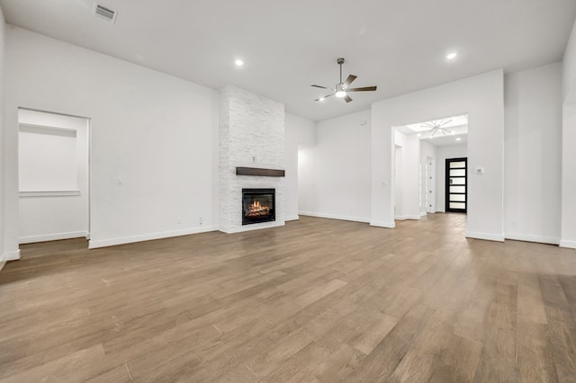 unfurnished living room featuring visible vents, wood finished floors, a fireplace, baseboards, and a ceiling fan