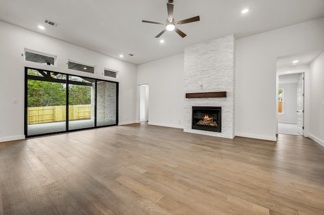 unfurnished living room featuring ceiling fan, recessed lighting, a stone fireplace, and wood finished floors