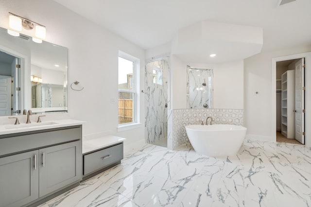 full bath featuring a walk in closet, vanity, a marble finish shower, marble finish floor, and a soaking tub