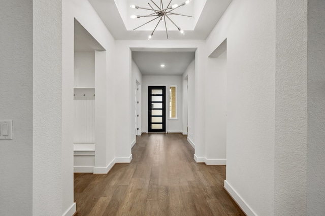 hallway with an inviting chandelier, baseboards, a textured wall, and wood finished floors