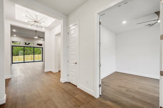 corridor with visible vents, wood finished floors, baseboards, recessed lighting, and a chandelier