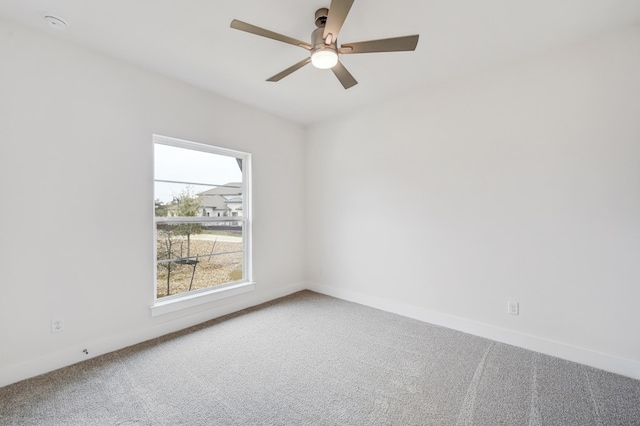 carpeted spare room with ceiling fan and baseboards