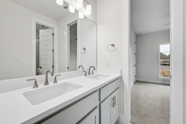 full bath with a sink, baseboards, double vanity, and visible vents