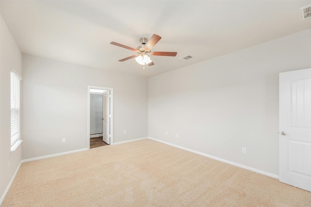 carpeted spare room featuring ceiling fan and plenty of natural light