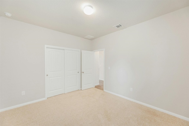 unfurnished bedroom with light carpet and a closet