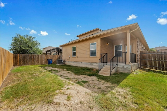 back of property featuring a yard and central AC