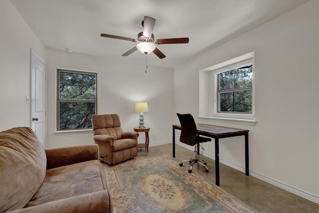 office featuring a healthy amount of sunlight, concrete flooring, baseboards, and a ceiling fan