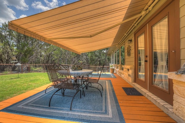 wooden terrace featuring outdoor dining space, a yard, and fence