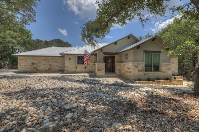 ranch-style house featuring stone siding and metal roof