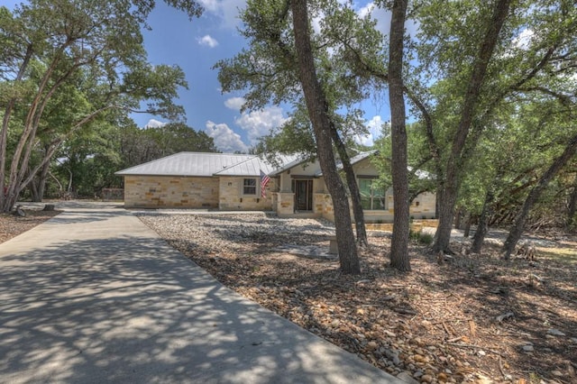 ranch-style home with metal roof and stone siding