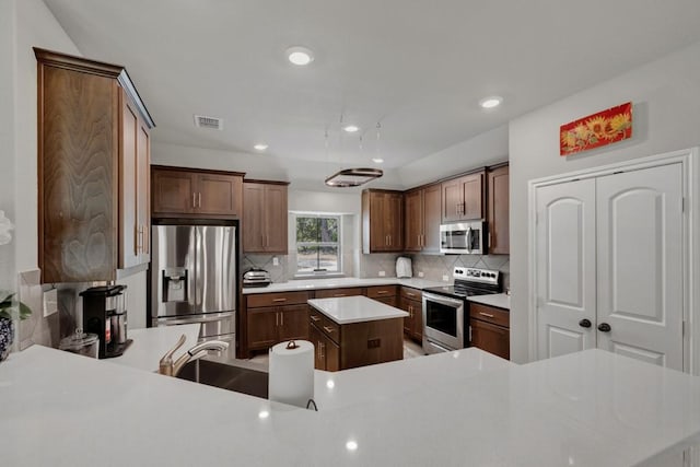 kitchen with visible vents, light countertops, appliances with stainless steel finishes, backsplash, and a kitchen island