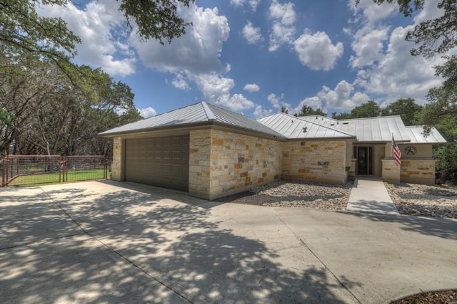 view of front facade featuring stone siding, metal roof, a garage, fence, and concrete driveway