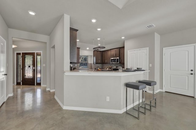 kitchen featuring stainless steel microwave, finished concrete floors, visible vents, and dark brown cabinets