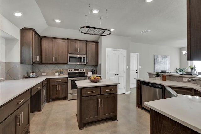 kitchen with concrete floors, a sink, dark brown cabinets, stainless steel appliances, and backsplash