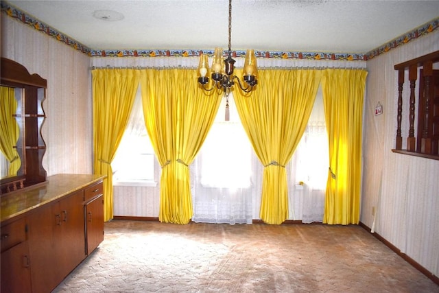 carpeted spare room with a chandelier and a textured ceiling