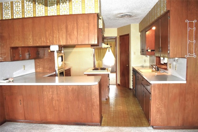 kitchen featuring kitchen peninsula, sink, a textured ceiling, and oven